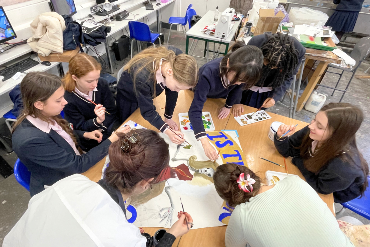 Students collaboratively paint a large piece of canvas
