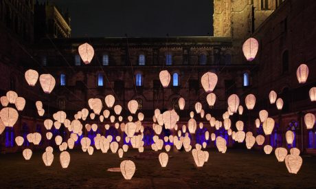 Lanterns illuminate the cloister of Durham Cathedral. Blue light emanates from the arches behind.