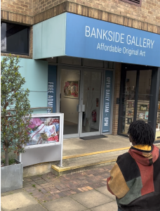 A person walks towards the entrance of a gallery with the words "Bankside Gallery: Affordable Original Art" written on the facade