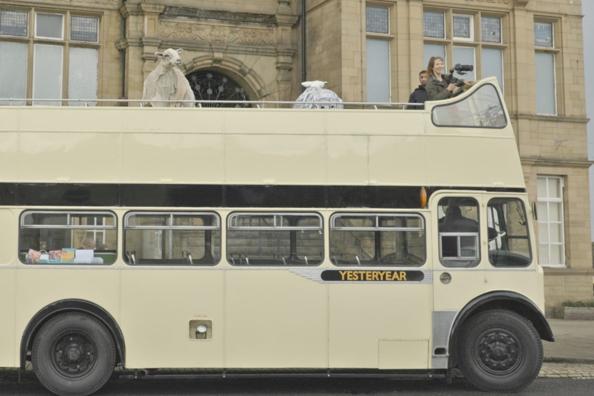 A cream-coloured vintage open-top double-decker bus marked 