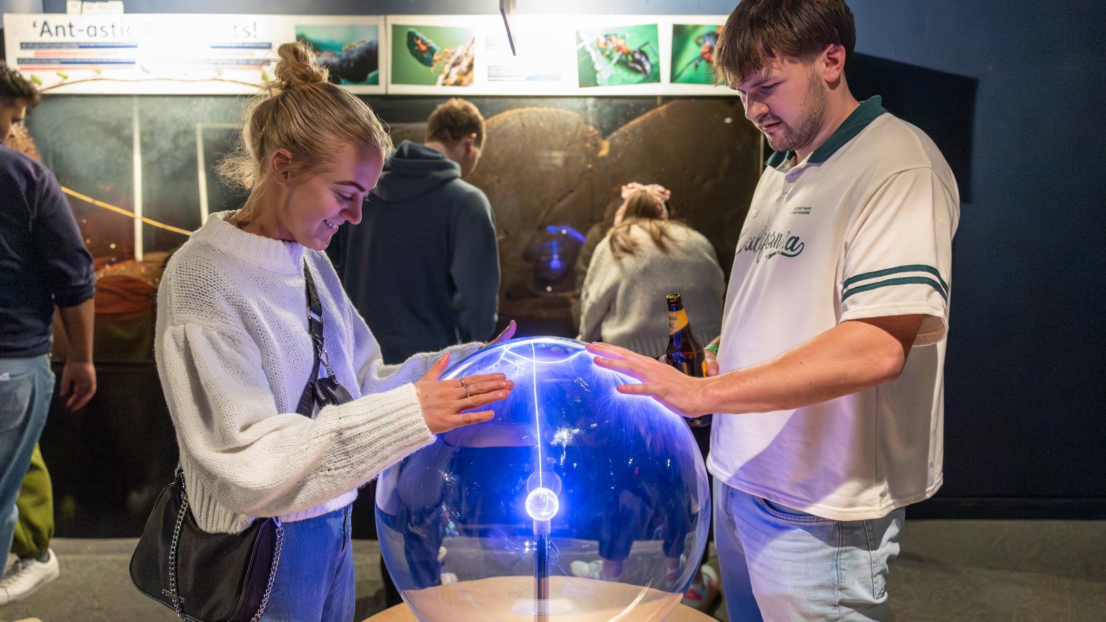 A young couple in Techniquest, making electricity move on the plasmasphere exhibit