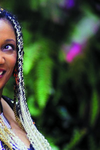 Juliet, with long braided hair, with a background of green and purple swirling lights