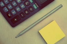 Photo of a calculator, pen and post-it note