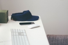 Photo of a desk with baseball cap, phone and computer