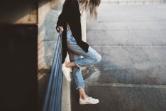 A sad student leaning against a fence