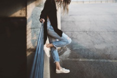 A sad student leaning against a fence 