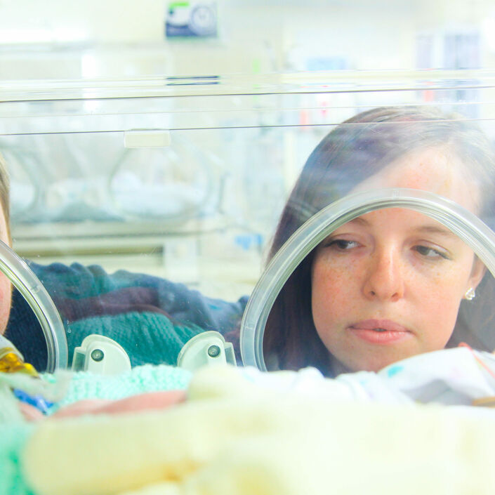 Mum and dad looking into incubator at baby