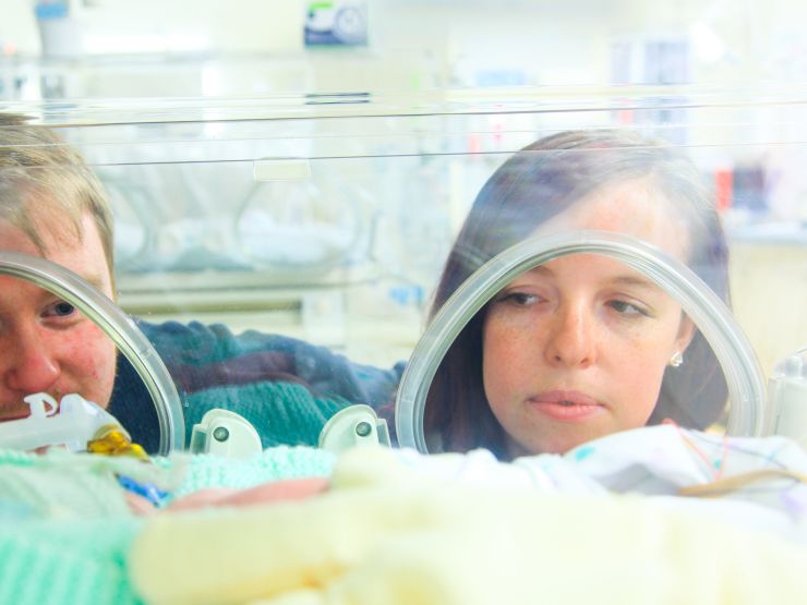 Mum and dad looking into incubator at baby