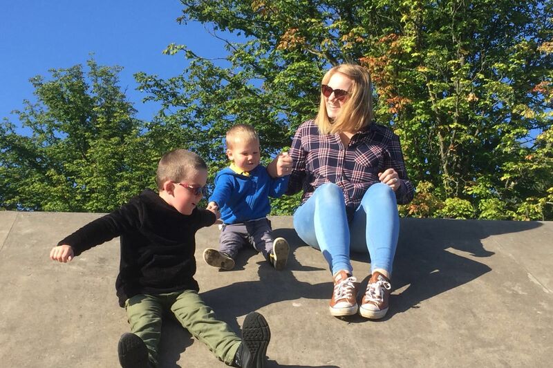 Bliss Champion Linda playing with two boys outside with trees in the background