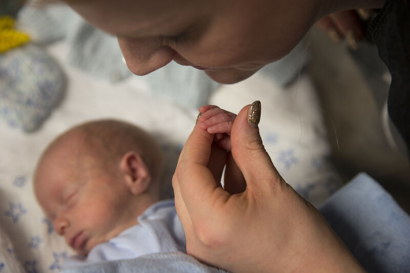 Baby asleep while mum holds his hand in hers
