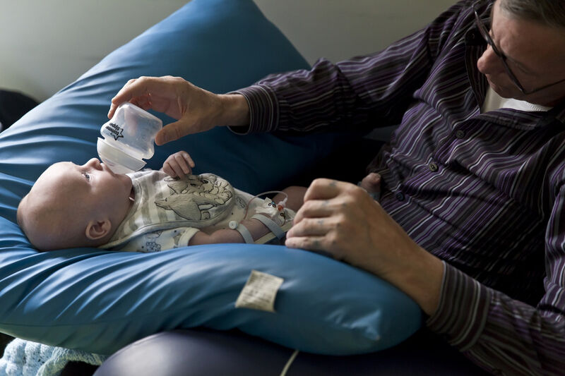 Baby resting on pillow with dad bottle feeding