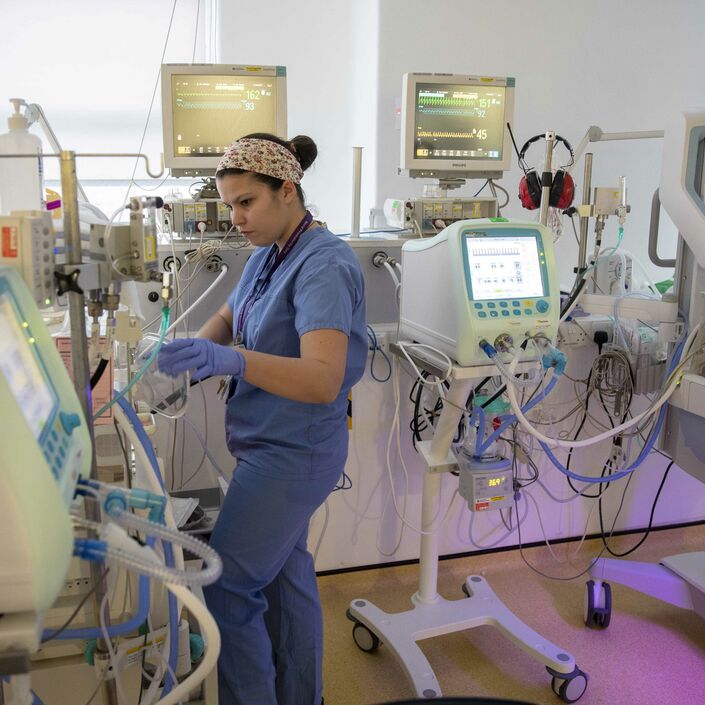 Neonatal nurse stands next to incubator look at the instrument readings
