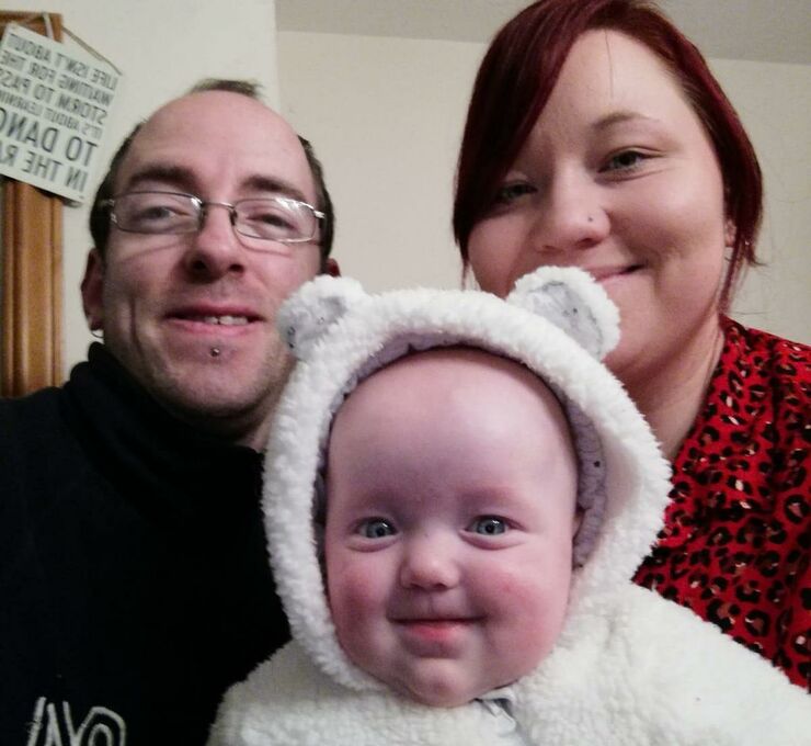 mum, dad and their baby daughter smiling