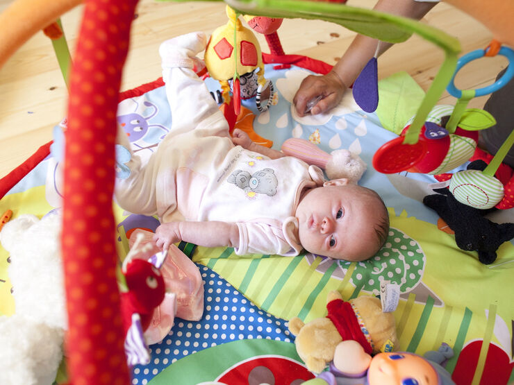 Baby in pyjamas lying on their back looking at elevated toys.