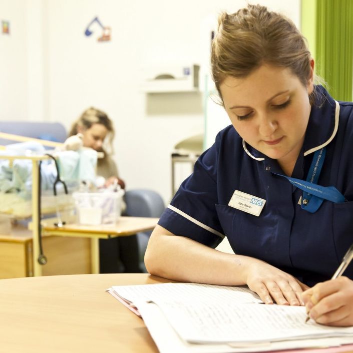 Nurse sat at a table making notes on a paper document