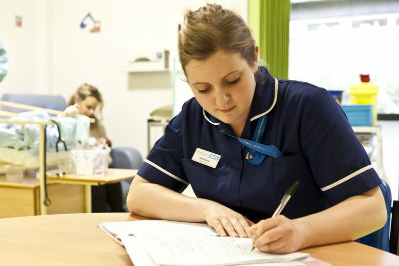 Nurse sat at a table making notes on a paper document