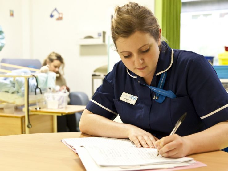 Nurse sat at a table making notes on a paper document