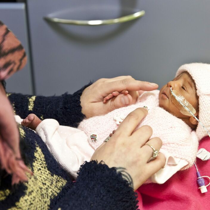 Mother holding her baby dressed in pyjamas on her lap