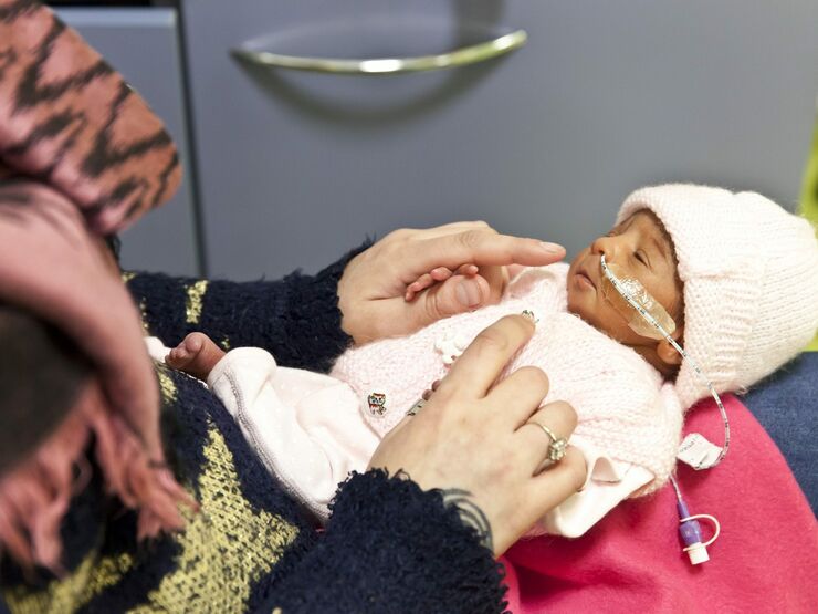 Mother holding her baby dressed in pyjamas on her lap