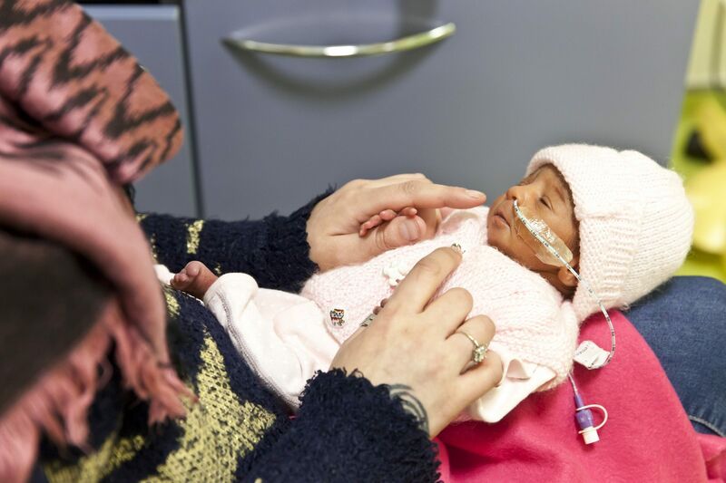 Mother holding her baby dressed in pyjamas on her lap