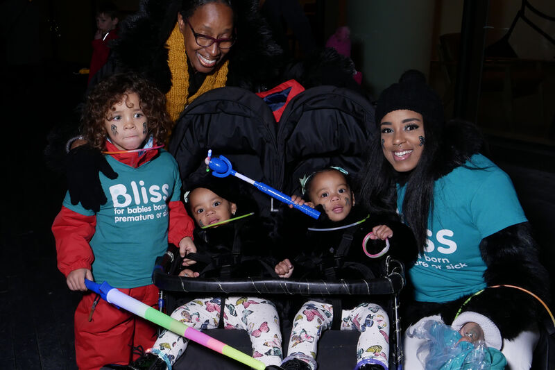 2 Adults, young child and 2 toddlers in a twin buggy wrapped up warm in darkness