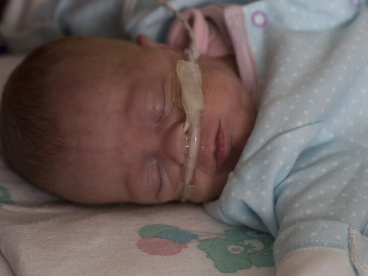 Baby in pyjamas sleeping peacefully with a tube attached to their nose