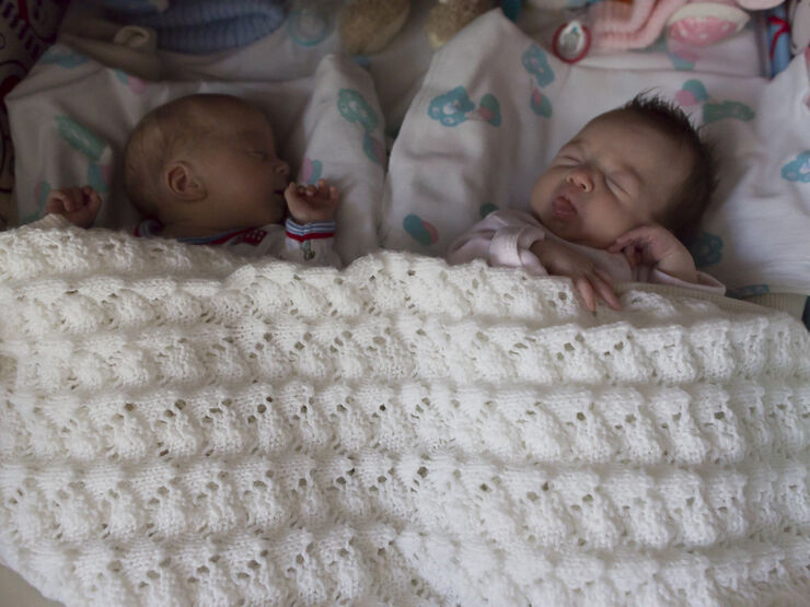 Twins sleeping peacefully next to each other underneath a blanket