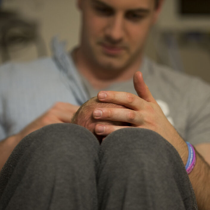 Dad with his baby lying on his lap, holding the baby's head