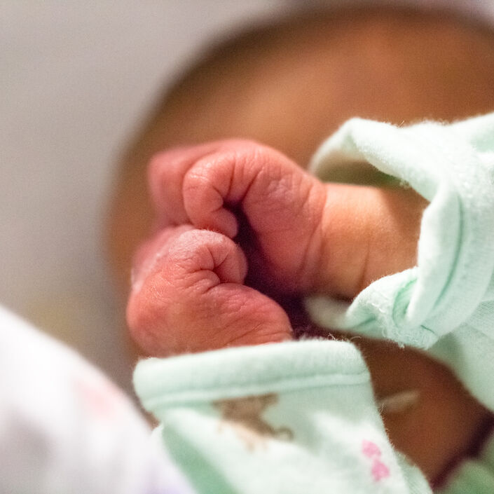 Baby in pyjamas with both hands clenched into fists