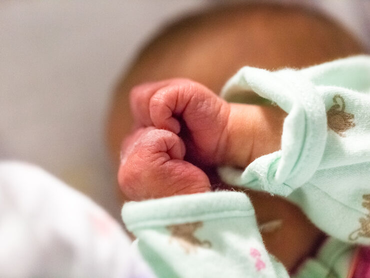 Baby in pyjamas with both hands clenched into fists
