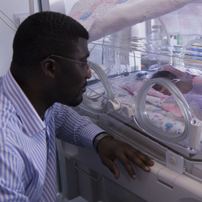 Father looking longingly at his child through an incubator