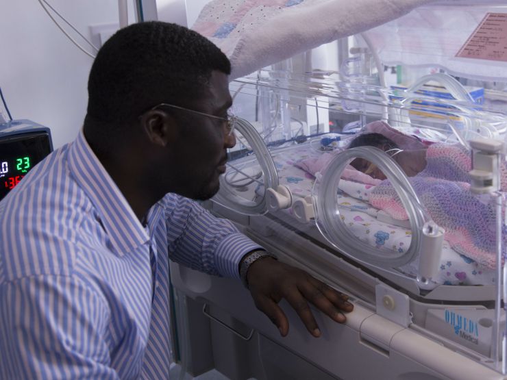 Father looking longingly at his child through an incubator