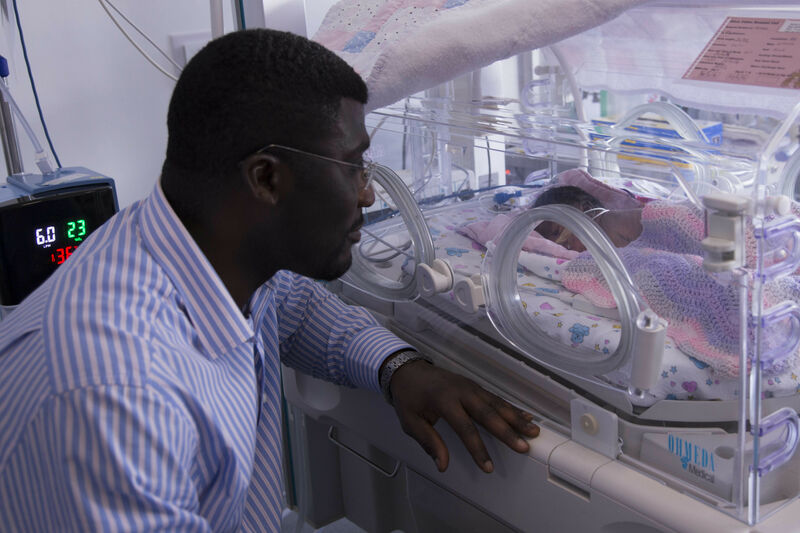 Father looking longingly at his child through an incubator