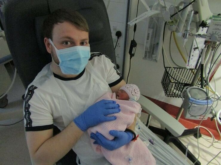 Tom holding his baby girl on the unit