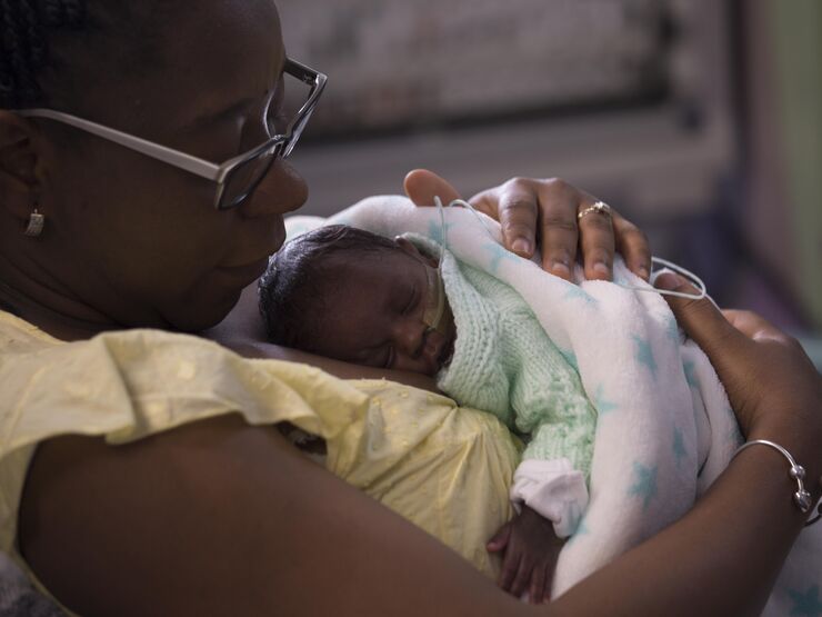 Mum holding her baby wrapped in a blanket on her chest