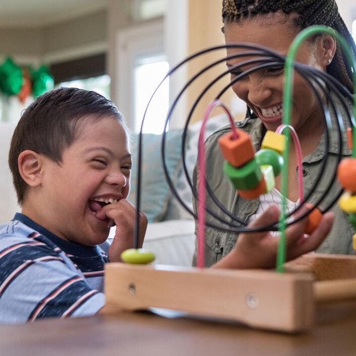 Mum and child happily playing with a toy, smiling and laughing