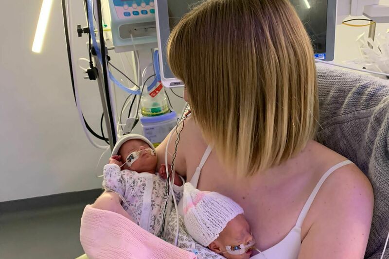 Abbie holding her twins in the NICU