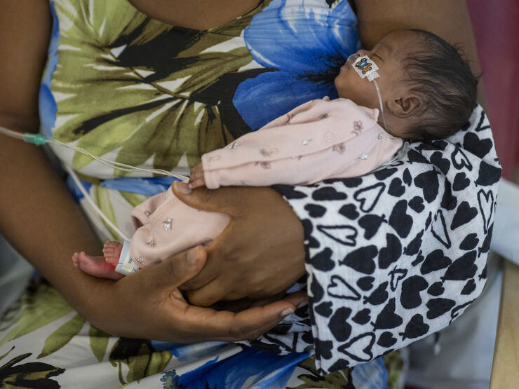Mum holds baby wearing pyjamas and attached to feeding tube in her arms