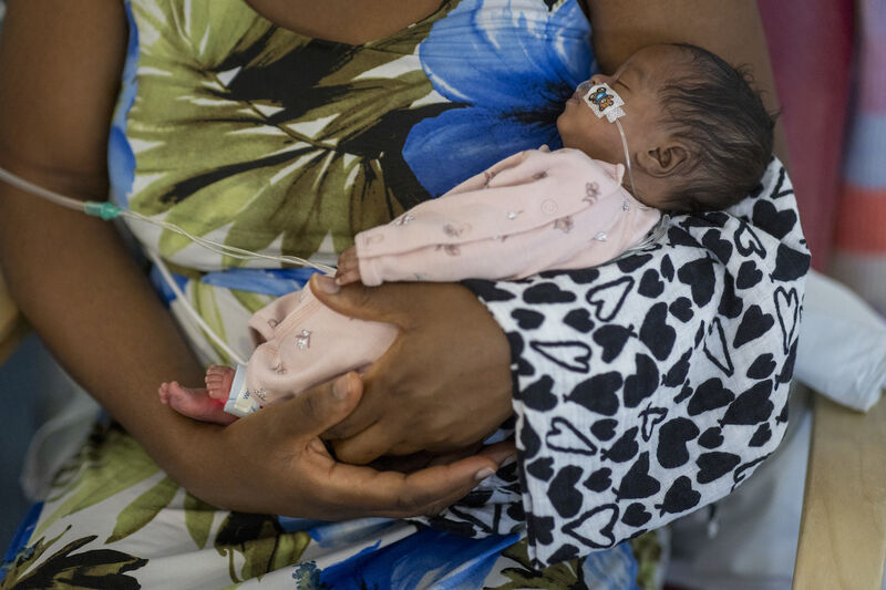 Mum holds baby wearing pyjamas and attached to feeding tube in her arms