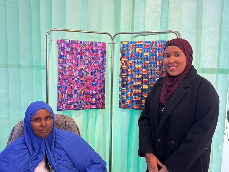 Artist Hafza Yusuf on the right, stood with a fellow community member stood in front of her artwork