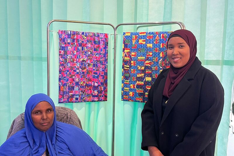 Artist Hafza Yusuf on the right, stood with a fellow community member stood in front of her artwork