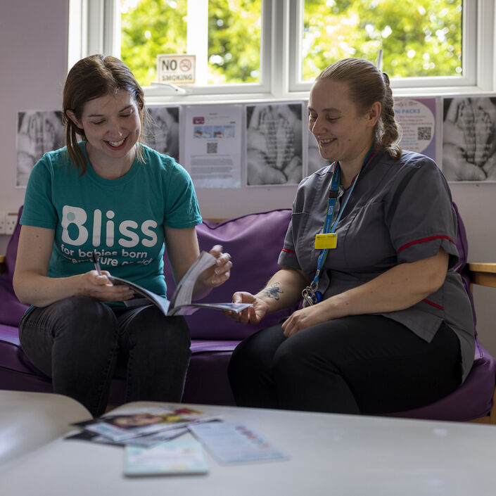 Nurse and Bliss representative sat on sofa both looking at an open booklet