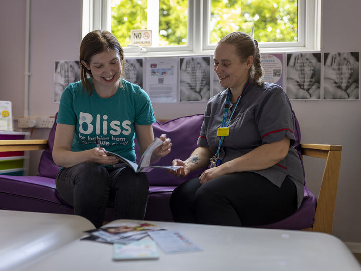 Nurse and Bliss representative sat on sofa both looking at an open booklet