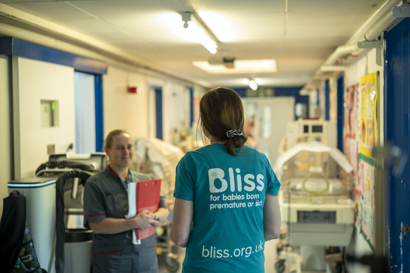 Volunteer wearing a Bliss t-shirt speaking with a nurse in a hospital setting