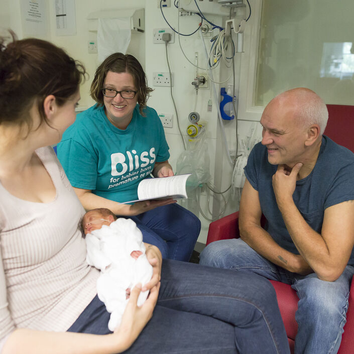 Bliss champion on a unit talking to parents with mum holding the baby