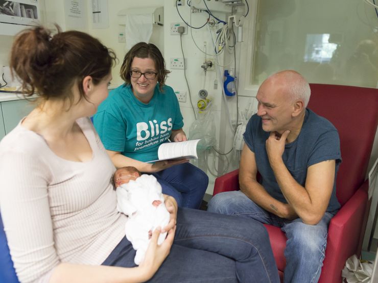 Bliss champion on a unit talking to parents with mum holding the baby