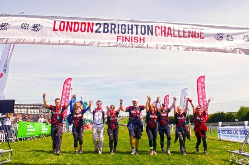Group of walkers holding hands and crossing the finish line together