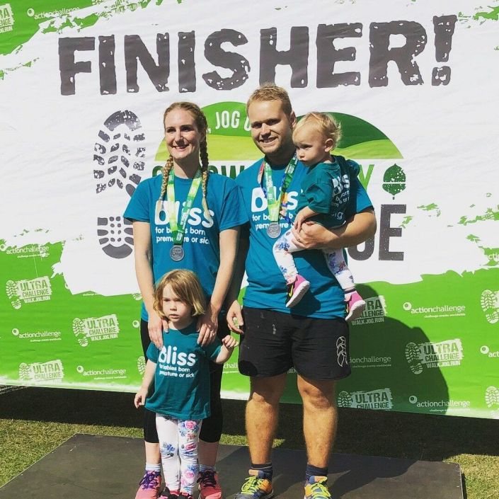 A family of 2 adults and 2 children wearing finisher event medals