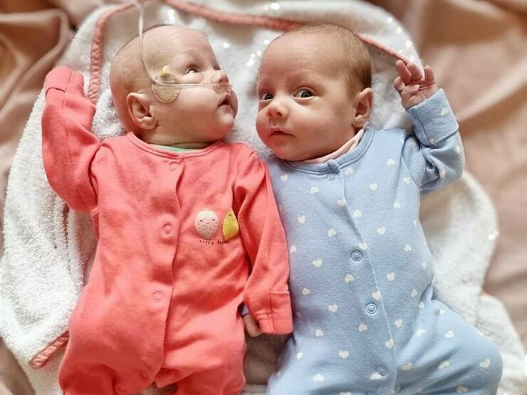 Twin babies wearing pyjamas lying on bed