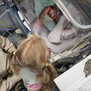 Sibling looking at premature baby in an incubator
